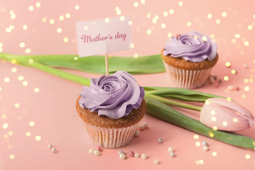 Tasty cupcakes, tulip and topper pick with words MOTHER'S DAY on color background