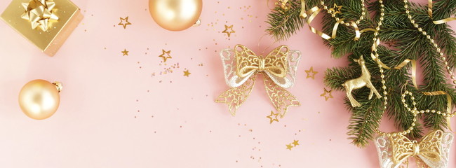 Christmas background banner. Xmas or new year gold color decorations on pink background with empty copy space for text.  holiday and celebration concept for postcard or invitation. top view 