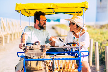 Adult cheerful caucasian people couple having fun outdoor with vacation double bike -together in relationship enjoying the outdoor leisure activity - defocused background