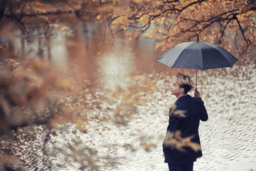 Autumn rainy weather and a young man with an umbrella