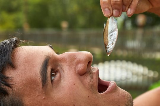 Man Holding A Tiny Fish Pretending To Eat It