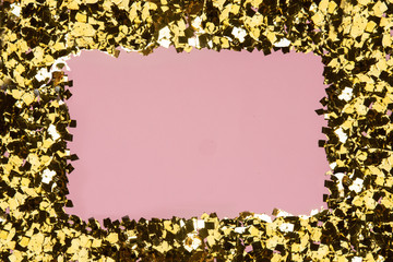Golden confetti glitter frame on pink background. Festive holiday pastel backdrop. Greeteng cards template.