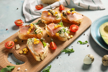 Wooden board with tasty sandwiches on table
