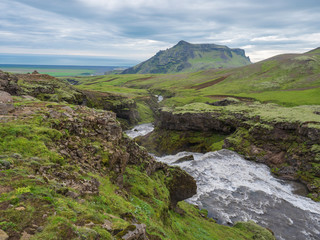 Beautiful lush green Landscape of Skoga river valley cascades near Skogafoss waterfall and Skogar end of Fimmvorduhals hiking trail. South Iceland, Summer blue sky