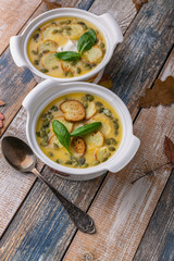 Two servings Autumn cream soup with vegetables, croutons, pumpkin seeds and fresh spinach on a rustic background. Vertical shot