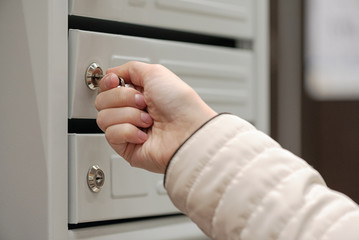 Woman open a mailbox by a key in her hands close up.