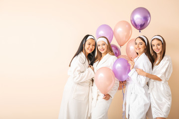 Beautiful young women in bathrobes and with air balloons on light background