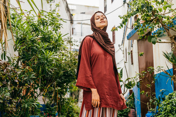 Muslim woman in Morocco on the background of buildings and an oleander