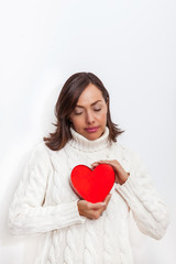 Beautiful sad woman holding a red heart on her hands isolated on white background.. Conceptual for heartbreak, cardiology.