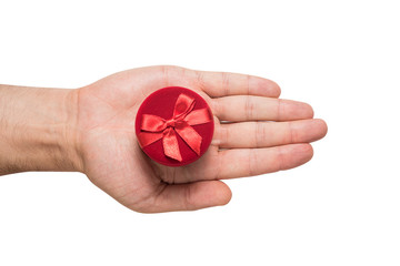 Open male palm with a round red jewelry box. Present. White background
