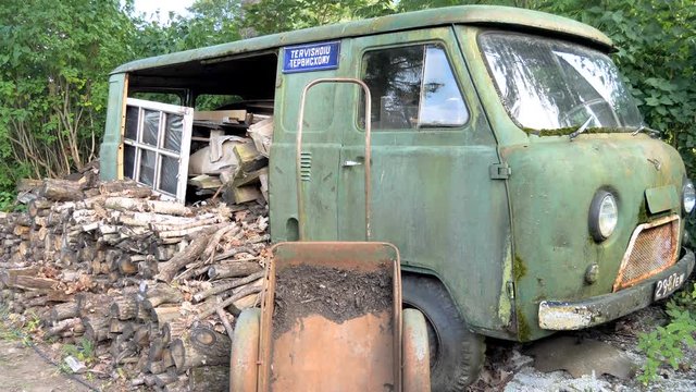The green old abandoned van on the side of the garage