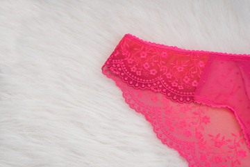 Part of lacy bright pink panties on white fur. Close up. Fashionable concept of lingerie