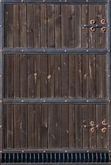 Brown wooden gate with forged metal stripes. Backgrounds and textures. Close up