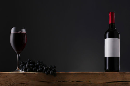 Bottle Of Red Wine With Label And Wineglass On Old Wooden Table