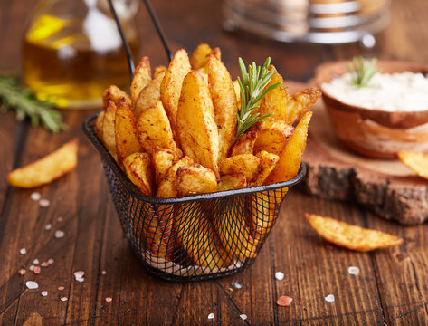 Potato wedges baked with rosemary. Delicious snack served with sauce. Fast food.