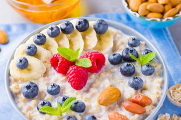 Healthy homemade oatmeal with berries and nuts for breakfast. Oatmeal with fruits, nuts and honey. Oatmeal with blueberries, banana and raspberries