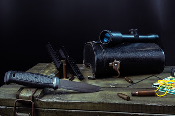 Large military knife and scope. Knife and sleeves on a military box.