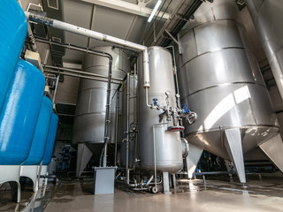 Drinking water factory or plant production, industrial interior. Large metal tanks for filtering and potable water treatment from well