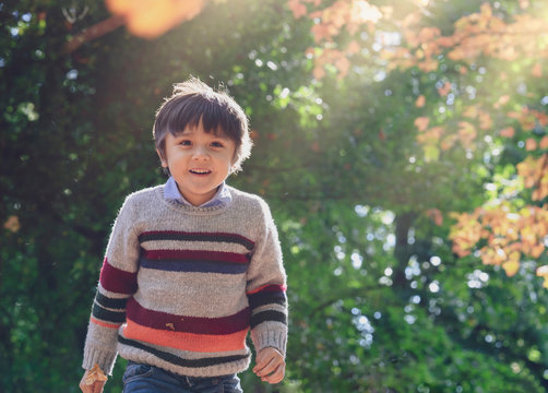 Active Boy With A Happy Face Having Fun Running Around On Green Grass,Healthy Kid Boy Wearing Colourful Jumper Playing Outdoors In The Park,Outdoor Activities For Children In Half Term Break On Autumn