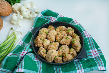 Fried breaded cauliflower. Dish in a small pan. White wood background.