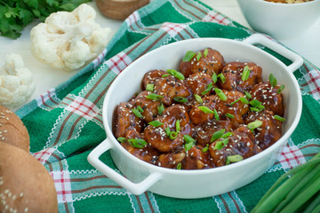 Fried Cauliflower in Sauce and Sesame. Asian style dish. White wood background.