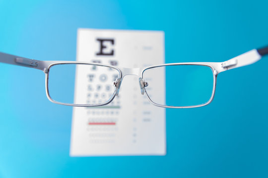 Hand-held glasses, view of the Snellen chart. Blue background