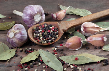 traditional spices for the kitchen. bay leaf, mixture of various peppers in a spoon and garlic on a...