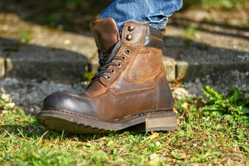 Man's leg in jeans and brown leather boot