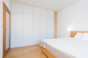 White wooden closet in bedroom of contemporary apartment - obrazy, fototapety, plakaty