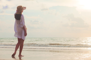 carefree woman in straw hat walking in the sunset on the beach. vacation vitality healthy living...