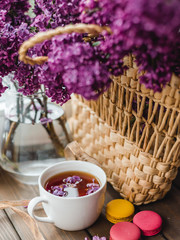 Romantic background with cup of tea, lilac flowers and macaroons. A bouquet of lilac in a vase. Floral card for Mothers or Womans Day