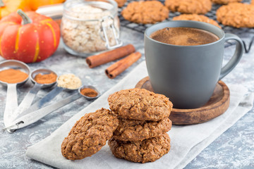Spicy pumpkin and oatmeal cookies on the table and on cooling rack, with cup of coffee, horizontal