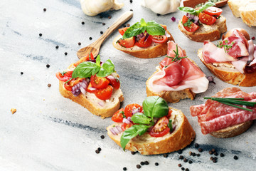 Assorted bruschetta with various toppings. Appetizing bruschetta or crudo crostini. Variety of small sandwiches. Mix bruschetta on table - obrazy, fototapety, plakaty