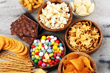 Salty snacks. Pretzels, chips, crackers in wooden bowls and candy and chocolate on table