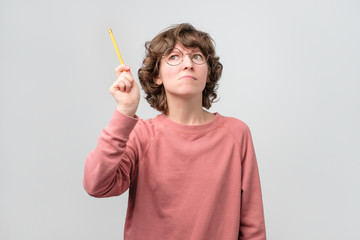 Young woman student holding finger with pencil up. Online education. Studio shot