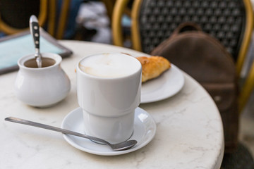 Delicious coffee with croissant. French breakfast concept. Cup of coffee on table oudoors at the cafe terrace