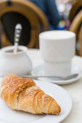 Delicious coffee with croissant. French breakfast concept. Cup of coffee on table oudoors at the cafe terrace