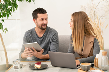 Confident businessman with touchpad looking at his colleague during discussion