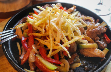 Meat roasted with vegetables and fried potatoes closeup, selective focus