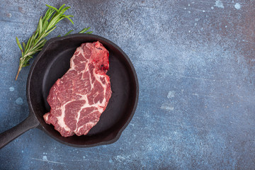 Raw chuck steak marbled beef on frying pan, with copy space, top view