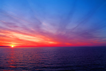 Colorful amazing sunset over the sea. Natural sunset, bright dramatic sky, red, pink and blue tones