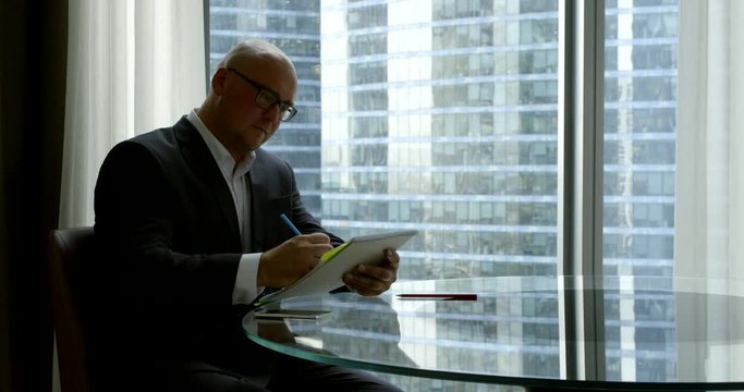 man with notebook and cell phone sits in office slow motion