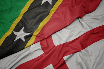 waving colorful flag of england and national flag of saint kitts and nevis.