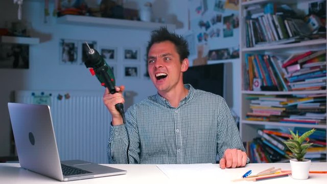The guy sits at the office desk shoots from a construction drill