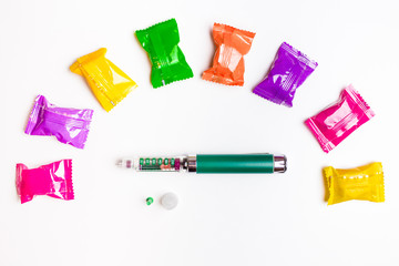 Diabetes green pen injection with colorful hard candies isolated on white