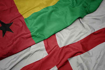 Fototapeta premium waving colorful flag of england and national flag of guinea bissau.