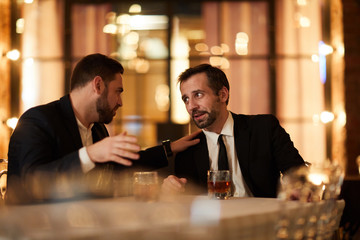 Portrait of two drunk business people talking while sitting at table in luxury restaurant after work