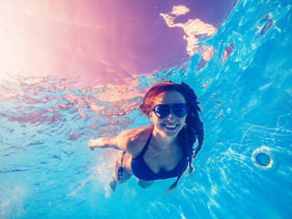 Swimming pool. A woman swims in the pool in sunglasses.