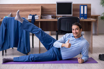 Young handsome businessman doing exercises at workplace