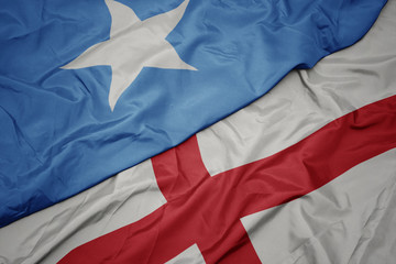 waving colorful flag of england and national flag of somalia.